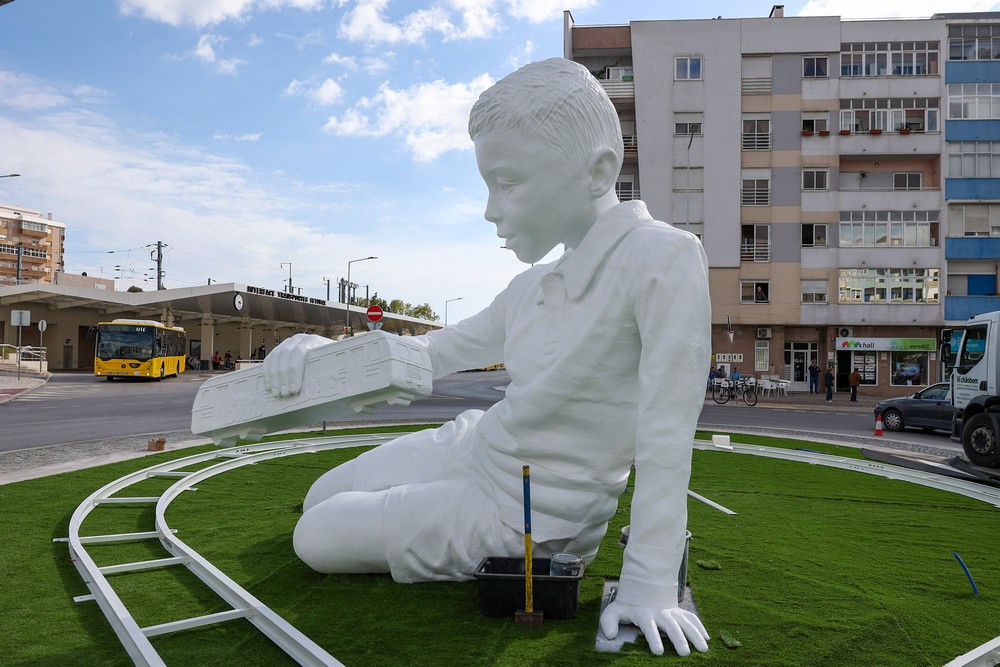 A escultura de um menino a brincar com um comboio numa linha infinita, de Ricardo Romero, começou a ser instalada na Rotunda da Praça do Brasil